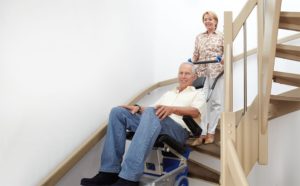 Osoba poruszająca się na schodołazie z pomocą opiekuna