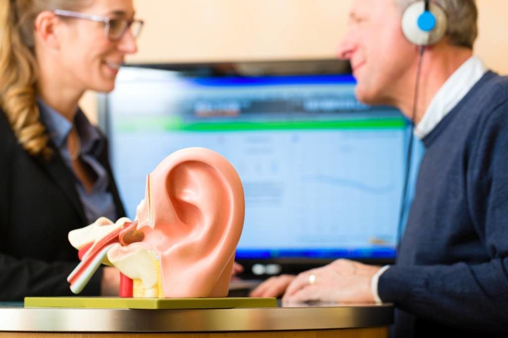 Protetyk słuchu prowadzi badanie słuchu audiometrem u mężczyzny