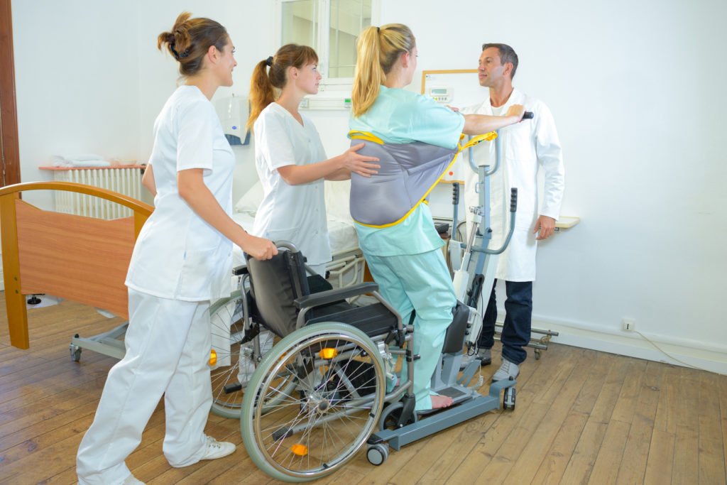 Pielęgniarka pomaga wstać z wózka przy użyciu pionizatora - brandvital.eu