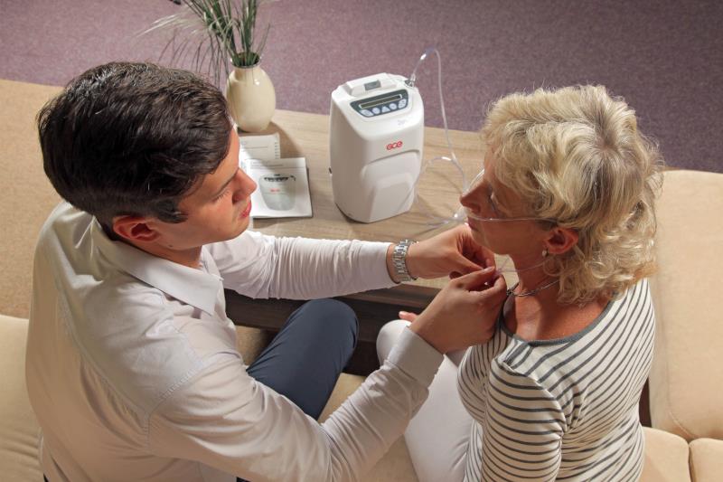 mężczyzna podpina koncentrator tlenu kobiecie