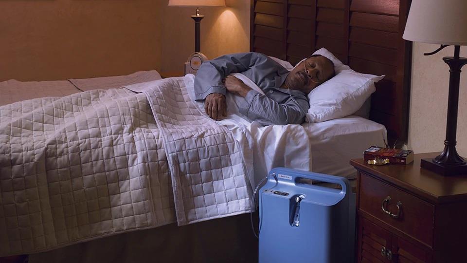 śpiący mężczyzna z koncentratorem tlenu