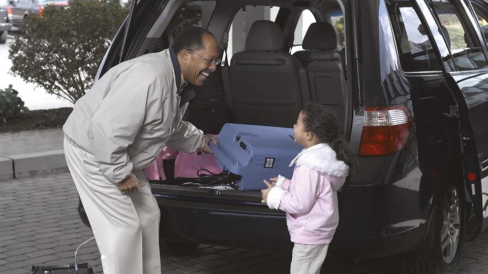 mężczyzna z dzieckiem chowający koncentrator tlenu